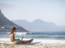 Mulher com laptop na areia da praia