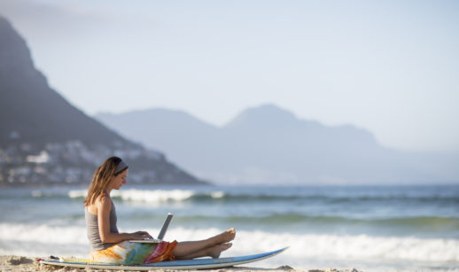 Mulher com laptop na areia da praia