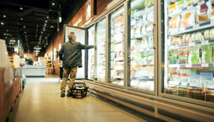 Geladeira de supermercado com homem abrindo uma das portas