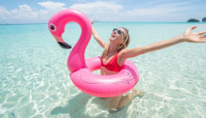 Viagens pós-covid. mulher com bois de flamingo na praia