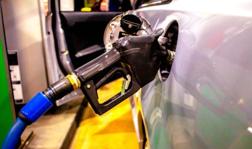 Bomba de combustível presa ao tanque de um carro, com preço da gasolina empurrando a inflação