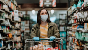 mulher com carrinho de supermercados fazendo compras de mascara