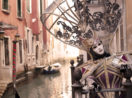 Pessoa com vestido e máscara de época no carnaval de Veneza, com um dos canais da cidade ao fundo