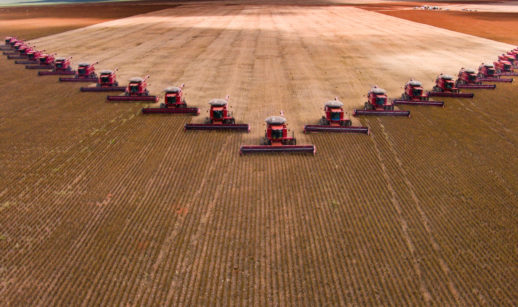 Emprego no agronegócio, com diversos tratores organizados em "V" em um campo de grãos