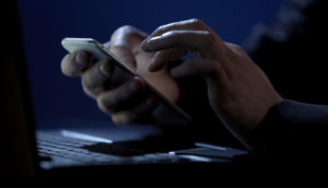 Hacker com celular na mão planejando vazamento de dados