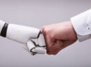 Mãos de robô com inteligência artificial e humano cumprimentando com soquinho