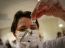 Vacina coronavac sendo sugada por agulha nas mãos de profissional de saúde