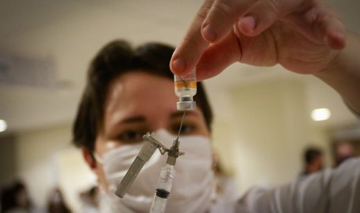 Vacina coronavac sendo sugada por agulha nas mãos de profissional de saúde