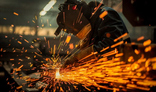 Produção industrial em fábrica com homem cortando metal