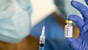 vacina e seringa na mão de médico