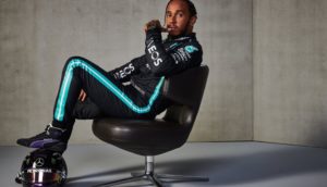Piloto de Fórmula 1 Lewis Hamilton setado em cadeira giratória com os pés em capacete