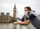Homem de colete, camiseta e máscara em ponte em frente ao relógio do Big Ben, em Londres
