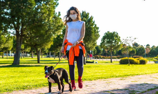 Mulher caminhando em parque com seu cachorro