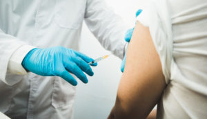 Braço de pessoa sendo vacinado por enfermeiro
