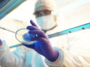 Cientista manipulando equipamentos de laboratório com roupa anti-infectante