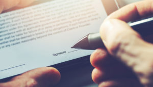 Close de pessoa assinando digitalmente um documento em tela de tablet com caneta da Clicksign