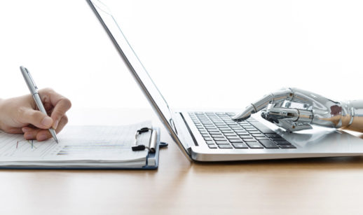 Mão de pessoa escrevendo em papel e mão de robô teclando em laptop do outro