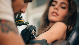 Tatuador remove tatuagem de mulher