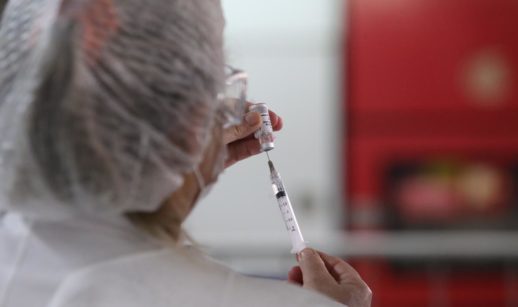 Enfermeira manipulando vacina contra a covid-19 em seringa