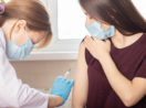 Enfermeira aplicando vacina contra a covid-19 em adolescente