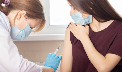Enfermeira aplicando vacina contra a covid-19 em adolescente