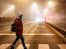 Pessoa atravessa rua no frio, de gorro e máscara