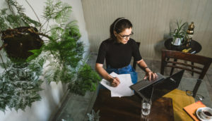 Mulher em mesa com computador e papéis no trabalho, buscando como ser mais produtiva