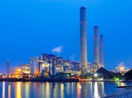 Foto de fábrica no início da noite com chaminés em destaque, em alusão às emissões e créditos de carbono