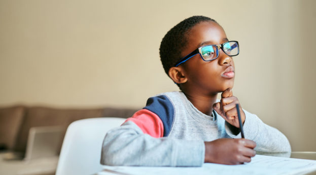 Criança negra de óculos estudando