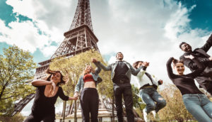 Pessoas felizes sem máscara pulando em frente a Torre Eiffel, em Paris, na França