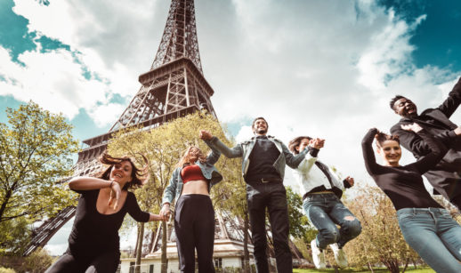 Pessoas felizes sem máscara pulando em frente a Torre Eiffel, em Paris, na França