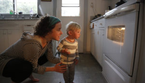 Mãe e criança olham forno do fogão