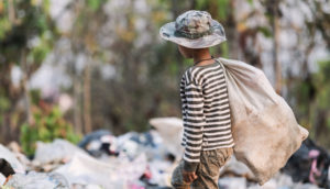 Criança caminhando em meio a aterro sanitário, em situação de trabalho infantil
