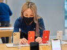 Vendedora da loja da Apple mexendo em modelos de iPhone
