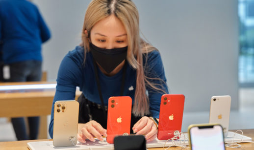 Vendedora da loja da Apple mexendo em modelos de iPhone