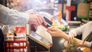 Pessoa pagando compras de mercado em caixa com cartão de crédito, alusivo à inflação 2021