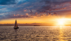 Barco à vela em paisagem com o pôr do sol, alusiva aos investimentos recomendados pelo Safra Report de julho