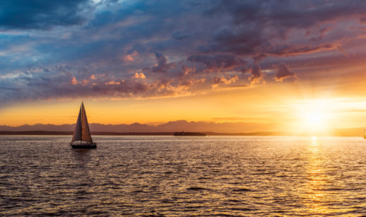 Barco à vela em paisagem com o pôr do sol, alusiva aos investimentos recomendados pelo Safra Report de julho