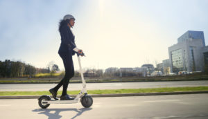 Mulher andando de patinete elétrico em rua, alusivo ao produto permitido pelo sandbox da Susep