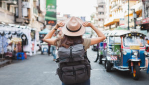 Mulher de costas com mochila e chapéu em viagem, em alusão a alguém que fez o checklist de viagem antes de partir