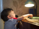 Criança apagando luz de luminária de mesa