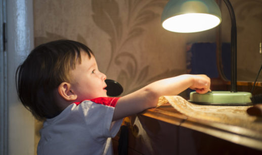 Criança apagando luz de luminária de mesa