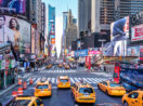 Foto de perspectiva de cima da Times Square, em Nova York, nos Estados Unidos, com táxis amarelos em destaque na rua
