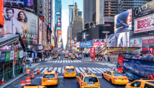 Foto de perspectiva de cima da Times Square, em Nova York, nos Estados Unidos, com táxis amarelos em destaque na rua