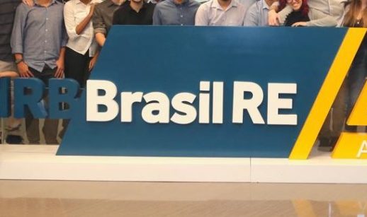 Placa da IRB Brasil RE com funcionários no entorno