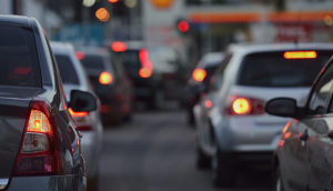 Trânsito visto de trás com veículos de lanterna de freio acesa, alusivo ao seguro de veículo