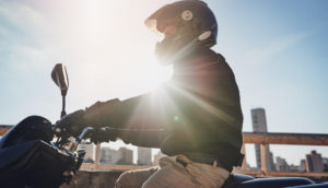 Motociclista andando de moto com sol ao fundo, alusivo às vendas de motos novas
