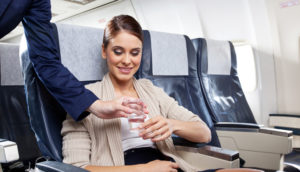 Aeromoça serve água a passageira de avião