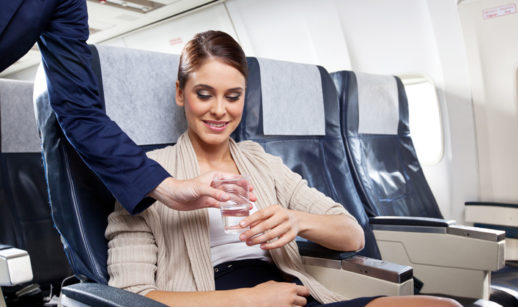 Aeromoça serve água a passageira de avião