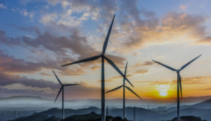 Campo de energia eólica com torres com o pôr do sol de fundo, alusivo à empresa Aeris, com ticker de ações AERI3